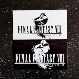 May include: Two square stickers, one black and one white, with the text "FINAL FANTASY VIII" in bold, black capital letters. Below the text is a stylized image of two figures embracing. Japanese text is below the main title.