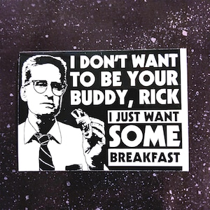 May include: Black and white sticker featuring a man in glasses with the text "I DON'T WANT TO BE YOUR BUDDY, RICK I JUST WANT SOME BREAKFAST". The sticker has a rectangular shape and is set against a speckled background.