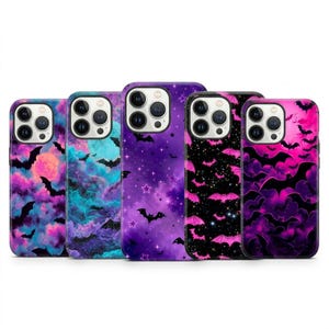 May include: Five smartphone cases featuring various designs of bats against colorful backgrounds. The patterns include purple and pink clouds, teal and blue nebula effects, a starry night sky, and repeating bat silhouettes in shades of pink and black.