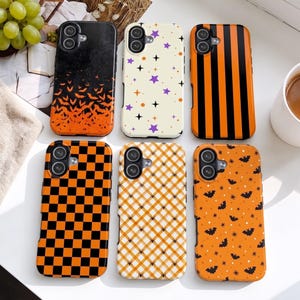 May include: Six rectangular smartphone cases featuring various patterns: a black-to-orange bat gradient, a cream background with purple stars and black sparkles, orange and black vertical stripes, a black and orange checkerboard, a plaid pattern with small spiders, and an orange background with black bats.