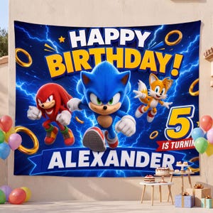 May include: A rectangular fabric backdrop featuring Sonic the Hedgehog, Knuckles, and Tails against a blue lightning background. The text reads HAPPY BIRTHDAY! 5 IS TURNING ALEXANDER. Gold rings are scattered across the design with a blue banner.
