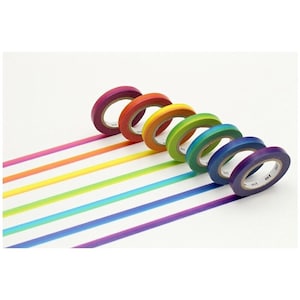 May include: A set of six rolls of adhesive tape arranged in a diagonal line, each featuring a distinct color of the rainbow including magenta, orange, yellow, lime green, teal, and purple, with the text mt printed on the inner cardboard core.