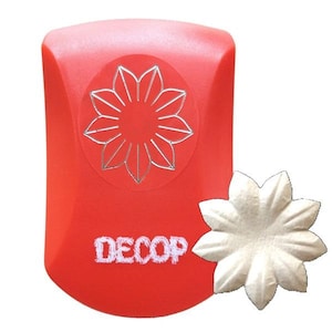 May include: A red craft punch with a silver flower design and the word "DECOP" in white. A white paper flower is next to the punch. This tool is used for paper crafting and scrapbooking.