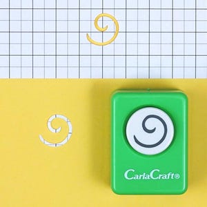 Puede incluir: Un remolino de papel amarillo y una perforadora de papel verde con un diseño de remolino blanco y negro. La perforadora tiene el texto "CarlaCraft®" en la parte delantera. El fondo es amarillo y blanco.