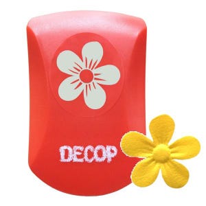 May include: A red craft punch with a white flower design and the word "DECOP" in white. A yellow felt flower is next to the punch. This tool is used for paper crafting and scrapbooking.