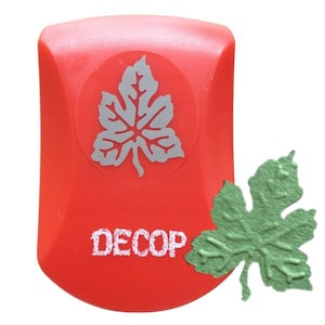 May include: A red craft punch with a gray leaf design and the word "DECOP" in white. A green leaf-shaped paper cutout is next to the punch. This tool is for paper crafting and scrapbooking.