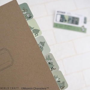 May include: A brown notebook with several light green and white Moomin character index tabs. The tabs feature illustrations of Moomin characters. The text "WORLD CRAFT" and "©Moomin Characters™" are visible at the bottom of the image.