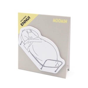 Op de afbeelding: Een grijs en wit Moomin-thema notitieblok. Het notitieblok heeft een witte illustratie van een Moomin-personage. De tekst "FACE SERIES ENNUI" is gedrukt op een gele hoek. Het woord "MOOMIN" is geel gedrukt.