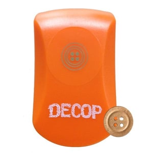 May include: Orange sewing tool with the word "DECOP" in white script. The tool has a circular design with a button graphic. A bronze-coloured button with four holes is next to the tool.