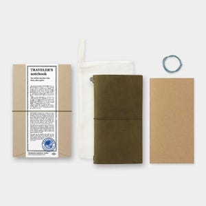 May include: An olive green leather Traveler's Notebook set with a matching refill, a canvas pouch, and a blue elastic band. The packaging includes a brown paper sleeve with the text "TRAVELER'S notebook".