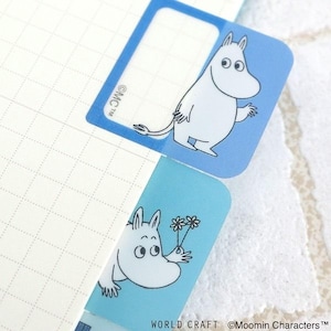 Op de afbeelding: Twee blauwe plaknotities met witte Moomin-personages. Eén Moomin-personage zwaait, de andere houdt bloemen vast. De bovenste plaknotitie heeft een leeg label. De tekst "WORLD CRAFT ©Moomin Characters™" staat onderaan.