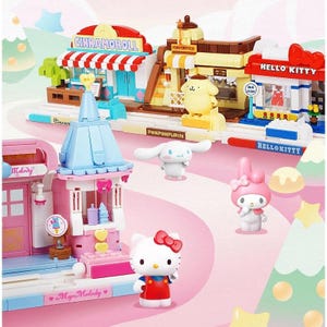 Op de afbeelding: Een kleurrijke speelgoed bouwset met miniatuurwinkels en karakterfiguren. De set bevat gebouwen met de labels "Cinnamoroll", "Hello Kitty", "My Melody" en "Pompompurin". De figuren zijn Hello Kitty, My Melody, Cinnamoroll en Pompompurin.