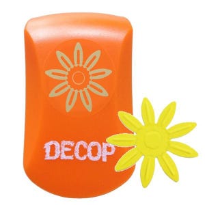 May include: An orange craft punch with a daisy design and the word "DECOP" in white. A yellow daisy shape is next to the punch. The punch has a rounded top and a rectangular body. The daisy design is in the centre of the punch.