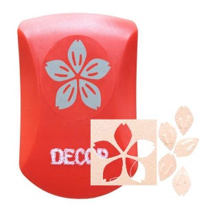 May include: A red craft punch featuring a light blue flower design. The punch has the word "DECO" printed on it. A cut-out flower and several petal shapes are also visible.