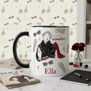 May include: White ceramic mug with a black handle and rim, featuring a fashion illustration with text. The design includes a woman in a fur coat, red high heel, and sunglasses. The mug has the name "Ella" and the quote "Details of your incompetence do not interest me."