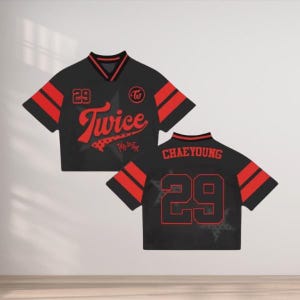 May include: Black and red cropped jersey with the word "Twice" in red script across the front. The number "29" is displayed on the front and back. The back of the jersey also displays the name "CHAEYOUNG".