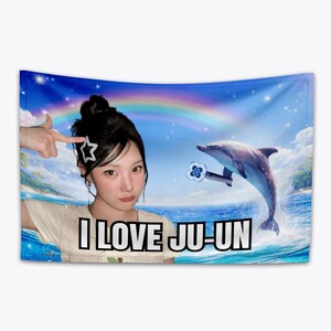 May include: A wall tapestry featuring a woman with a star-shaped hair clip, a dolphin, and a rainbow against a blue sky. The text "I LOVE JU-UN" is displayed at the bottom of the tapestry.