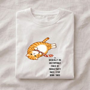 Può includere: T-shirt bianca con un gatto tabby arancione dei cartoni animati con una cravatta a righe rosse e bianche. Il gatto è sdraiato con il testo "Basically an unstoppable force of productivity once I stop being tired."