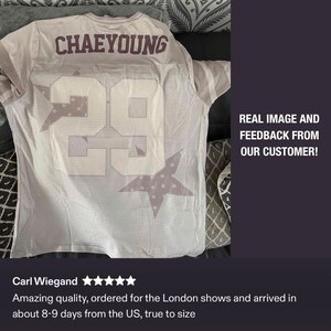 May include: A light-colored jersey with the name "CHAEYOUNG" across the upper back and the number "29" on the back and front. The number and name are in a darker color. The jersey has a star design.