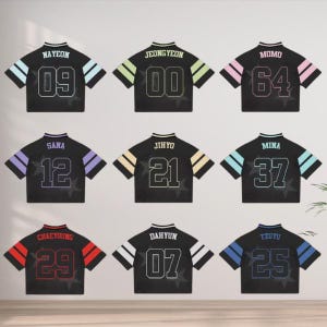 May include: Nine black crop tops with different names and numbers. Each top has a different color scheme on the sleeves and the name and number on the back. The names include NAYEON, JEONGYEON, MOMO, SANA, JIHYO, MINA, CHAEYOUNG, DAHYUN, and TZUYU.