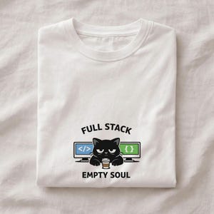 Peut inclure: T-shirt blanc avec un motif représentant un chat noir tenant une tasse de café, encadré par des écrans d'ordinateur avec des symboles de code. Le texte indique "FULL STACK EMPTY SOUL".