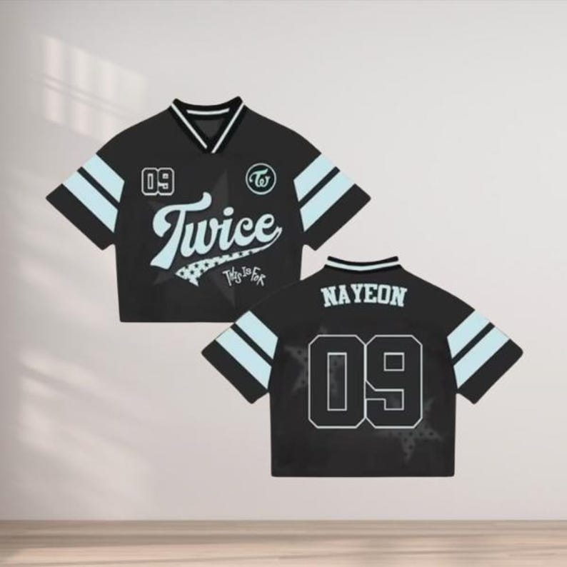 May include: Black crop top jersey with light blue stripes and accents. The front features the word "Twice" in white script, the number "09", and a logo. The back displays "NAYEON" and the number "09".