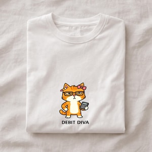 May include: White t-shirt featuring a cartoon cat with glasses, a pink bow, and a calculator. The cat is orange and white with a pencil behind its ear. The text "DEBIT DIVA" is printed below the cat.