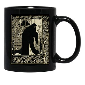 May include: A black ceramic mug featuring a cream-colored rectangular illustration of a cloaked figure in a garden setting. The artwork is enclosed within an intricate border of stylized vines and floral motifs, creating a high-contrast visual design.