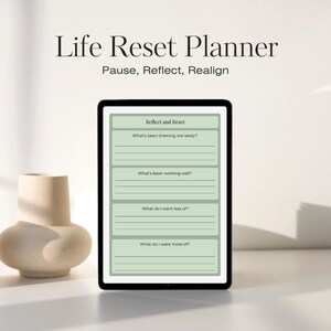 Może przedstawiać: Tablet cyfrowy wyświetlający "Life Reset Planner" z pytaniami do refleksji. Ekran pokazuje sekcje do samooceny, w tym pytania o to, co Cię wyczerpuje i co dobrze działa. Po lewej stronie znajduje się beżowy wazon.