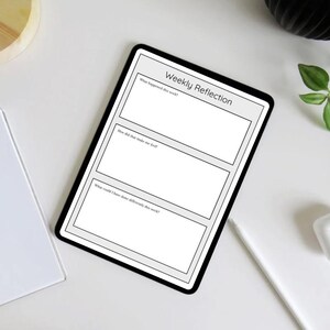 Könnte beinhalten: Ein schwarzes digitales Tablet mit einer Vorlage für "Wöchentliche Reflexion" mit drei Abschnitten zum Journaling. Das Tablet hat einen weißen Bildschirm mit schwarzem Text. Ein weißer Notizblock, ein Bleistift und kabellose Ohrhörer sind ebenfalls sichtbar.