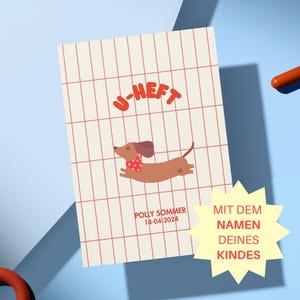 Könnte beinhalten: Ein Notizbuch mit einer Dackel-Illustration, die einen roten Schal mit Herzen trägt. Das Notizbuch hat den Text "U-HEFT" in Rot, und der Name "POLLY SOMMER 14-04-2024" ist darunter gedruckt.