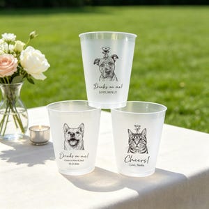 May include: Three frosted plastic cups featuring black ink illustrations of pets. The top cup shows a dog with the text "Drinks on me! LOVE, MOLLY". The bottom left cup shows a dog with "Drinks on me! Cheers to Mom & Dad 09.23.2026". The bottom right cup shows a cat with "Cheers! LOVE, SIMBA".