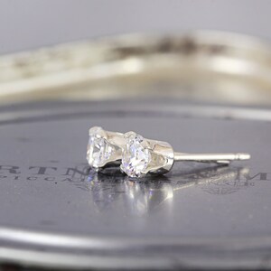 May include: A pair of silver stud earrings with clear round cubic zirconia stones.