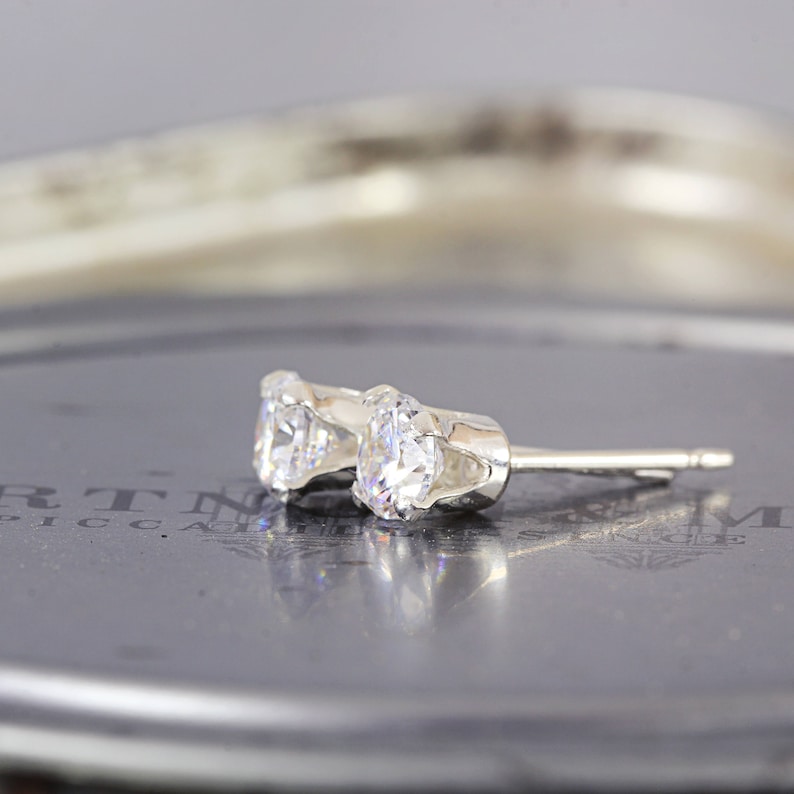 May include: A pair of silver stud earrings with clear round cubic zirconia stones.