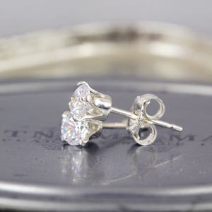 May include: A pair of silver stud earrings with a clear round cubic zirconia stone.