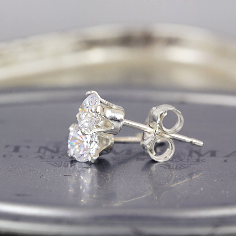 May include: A pair of silver stud earrings with a clear round cubic zirconia stone.