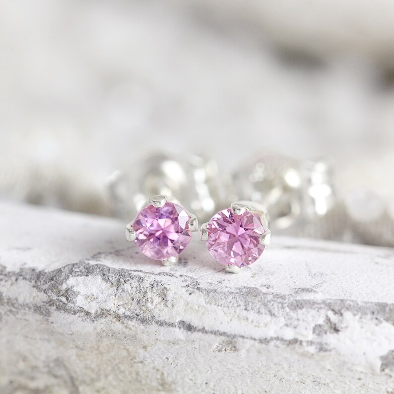 May include: A pair of silver stud earrings with small, round, pink gemstones.