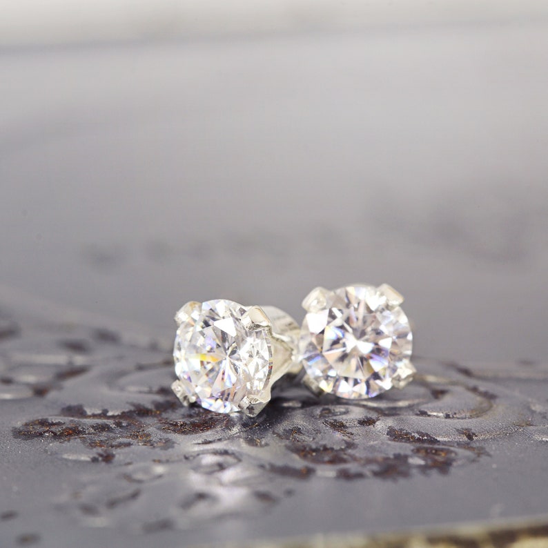 May include: A pair of silver stud earrings with clear round cubic zirconia stones.