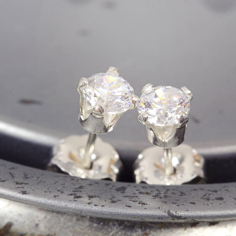 May include: A pair of silver stud earrings with clear round cubic zirconia stones.