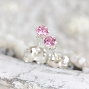 May include: A pair of silver stud earrings with pink gemstones.