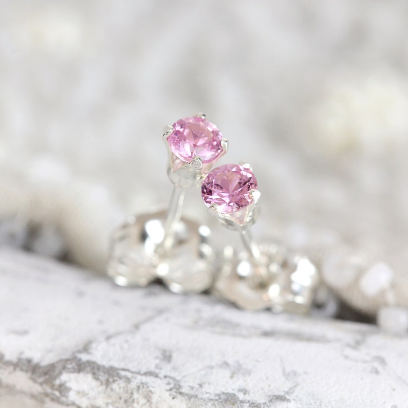 May include: A pair of silver stud earrings with pink gemstones.