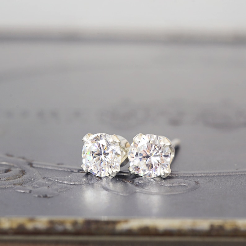 May include: A pair of silver stud earrings with clear round cubic zirconia stones.