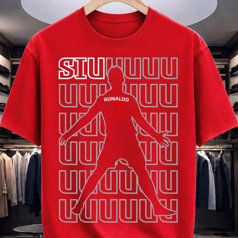 May include: Red t-shirt featuring a silhouette of a soccer player with outstretched arms. The shirt has the word "SIU" in white block letters at the top, and the name "Ronaldo" and the number "7" are visible on the player's jersey.