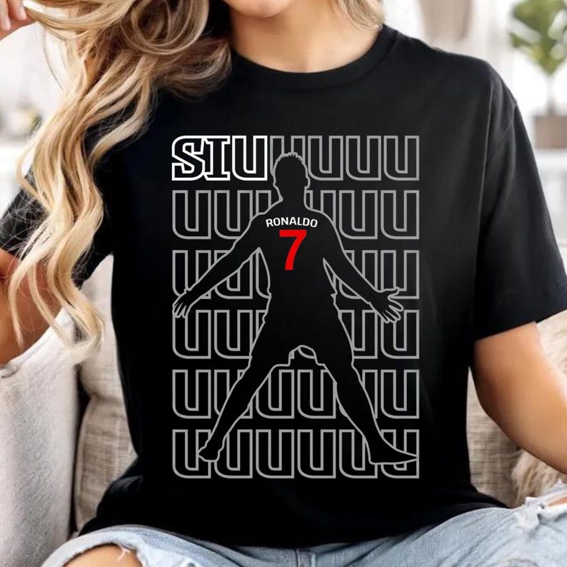 May include: Black t-shirt featuring a silhouette of a soccer player with the number 7 in red. The shirt has the word "SIUUUU" in white above the silhouette and the name "RONALDO" in white above the number 7.