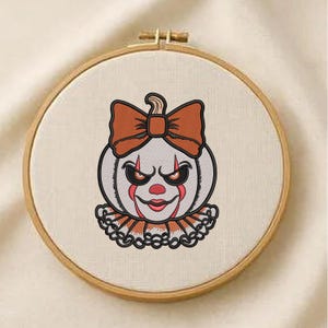 May include: An embroidered Halloween design of a pumpkin-shaped clown face with a bow, ruffled collar, and a menacing expression. The design is in a wooden embroidery hoop, ideal for seasonal decor.