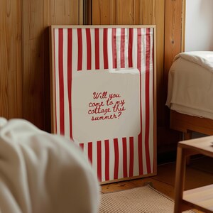 May include: A framed art print with a red and white striped background. The print features a white rectangular shape with the text "Will you come to my cottage this summer?" in red script. The frame is a light wood color.