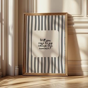 May include: A framed print with a gold border. The print features a cream-colored background with vertical gray stripes. A cream-colored rectangle in the center contains the text: "Will you come to my cottage this summer?"