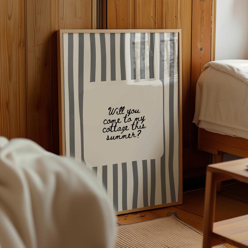 May include: A framed print with a light wood frame. The artwork features vertical gray and white stripes with a white rectangle in the center. The text "Will you come to my cottage this summer?" is written in black script.