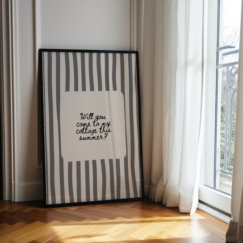 May include: Framed art print with a black frame. The artwork features a white background with a gray striped pattern and a central white square containing the text: "Will you come to my cottage this summer?" The print is leaning against a wall.