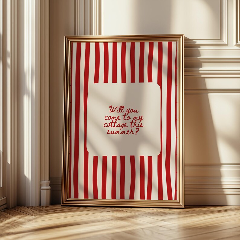 May include: A framed print with a gold border. The print features a red and white striped background with a central off-white rectangle. The rectangle contains the text: "Will you come to my cottage this summer?"